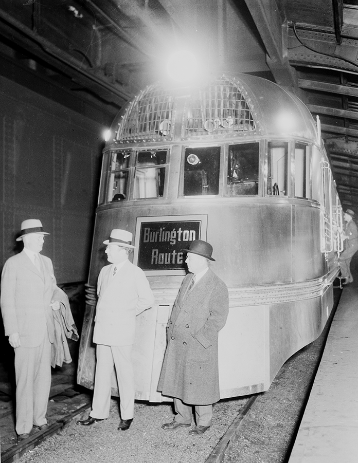 Man stand in front of a locomotive at rest on a track