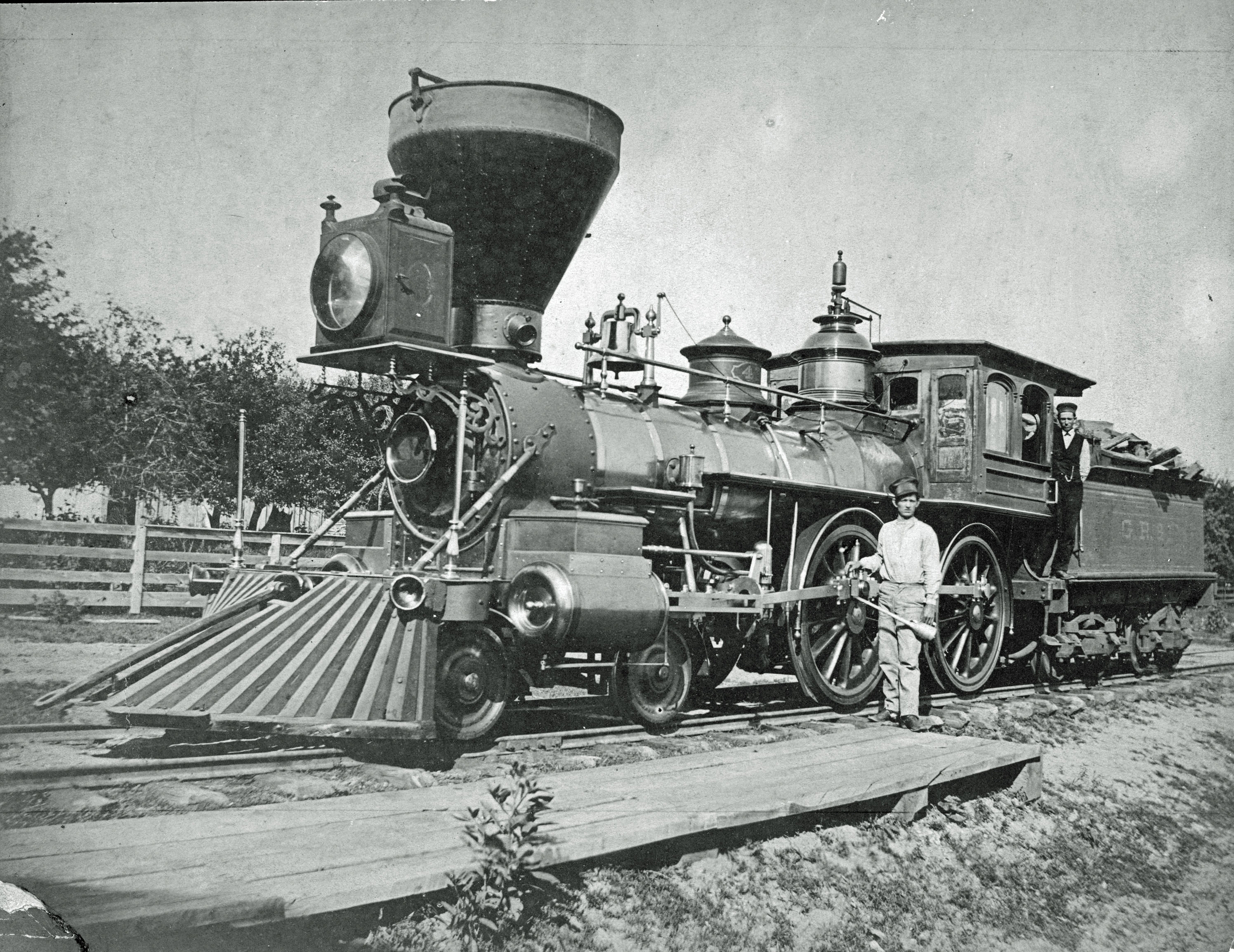 An engineer stands next to a locomotive with the Grand Rapids and Indiana Railroad, circa 1876