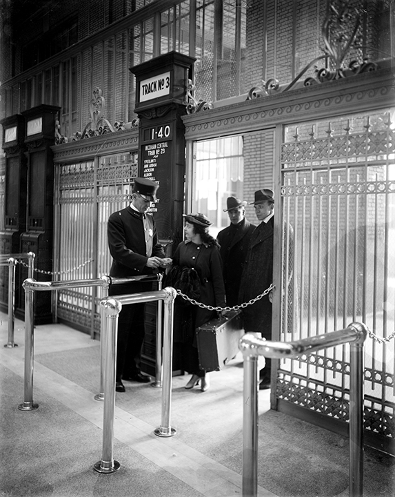 Three people at a ticket gate in the Michigan Central Station in Detroit