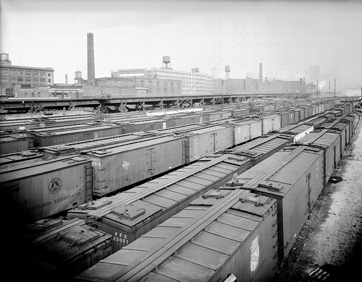 Long lines of railroad cars stand on tracks in a railroad yard