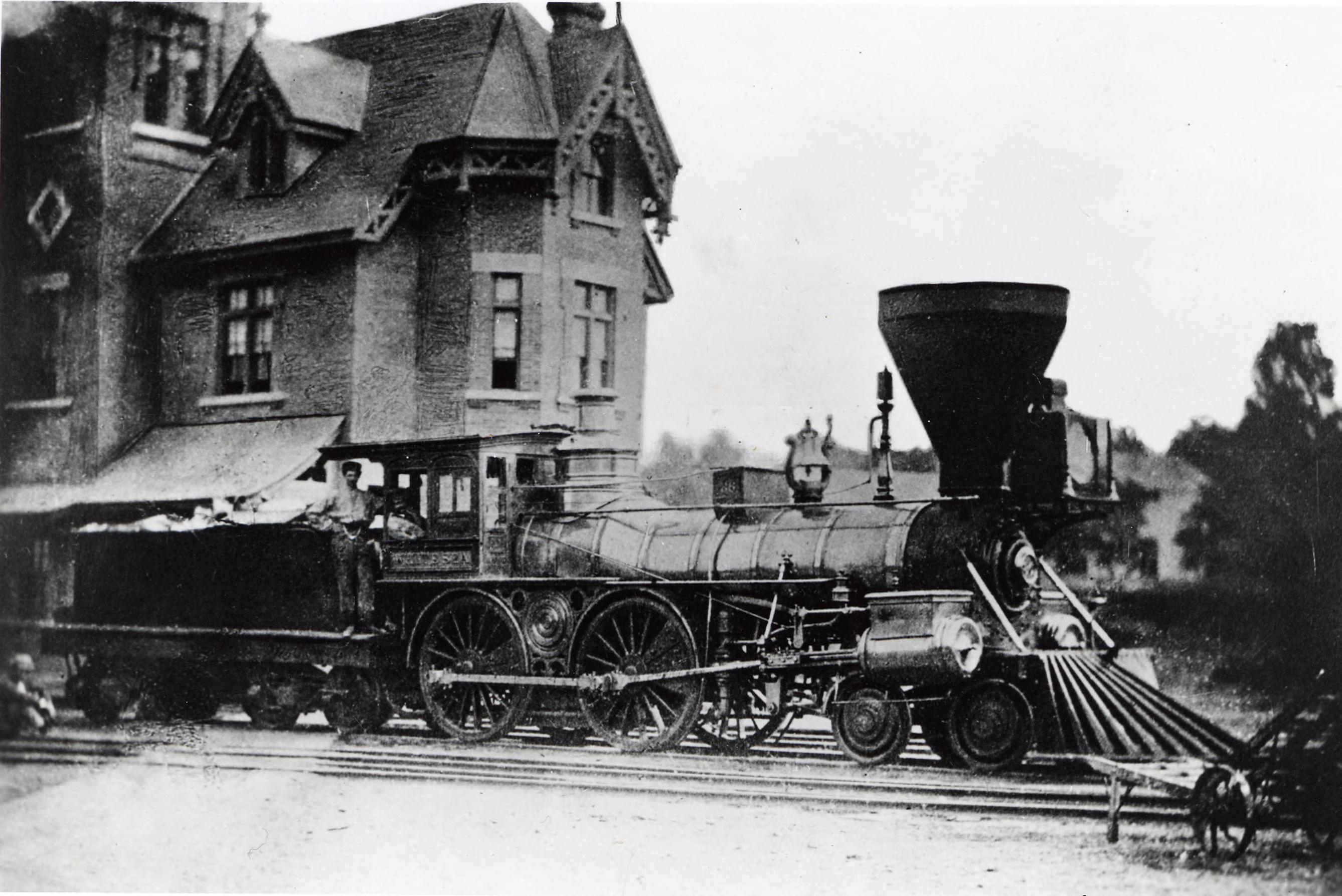 A locomotive on tracks next to a train depot