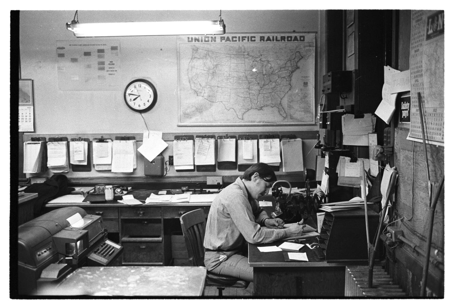A man sits at a dispatcher's desk in an office in the Ann Arbor railroad depot