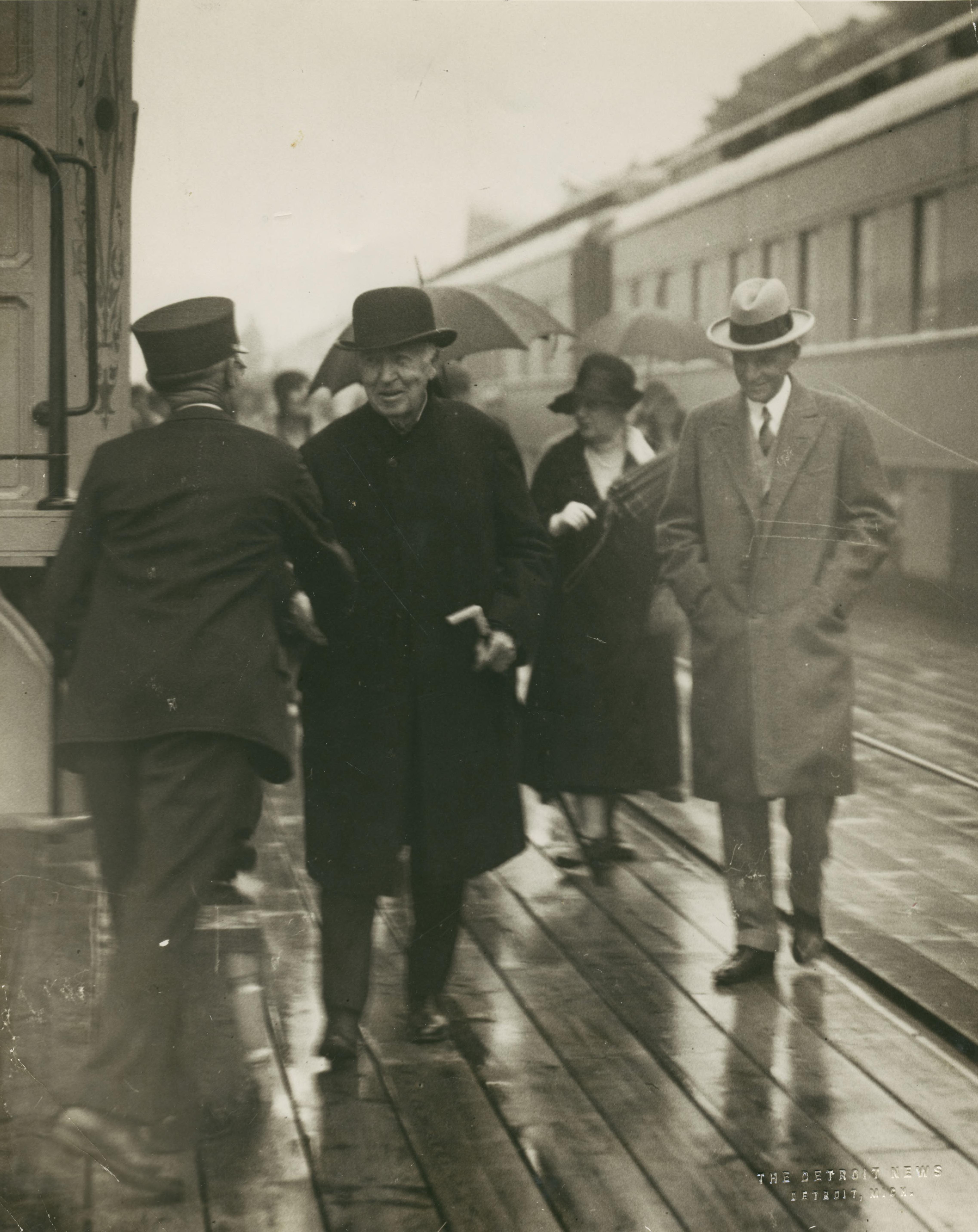Thomas Edison and Henry Ford stand outside a railroad depot in Ypsilanti