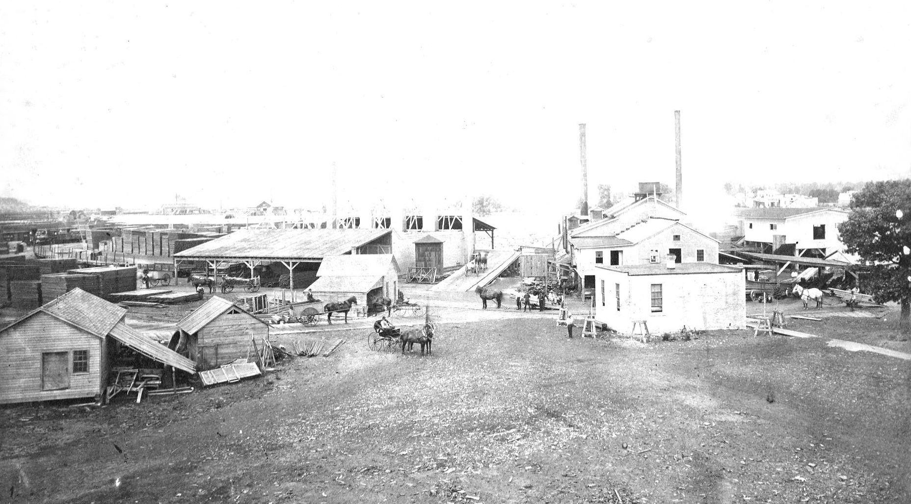 A lumber camp with buildings and horse drawn wagons