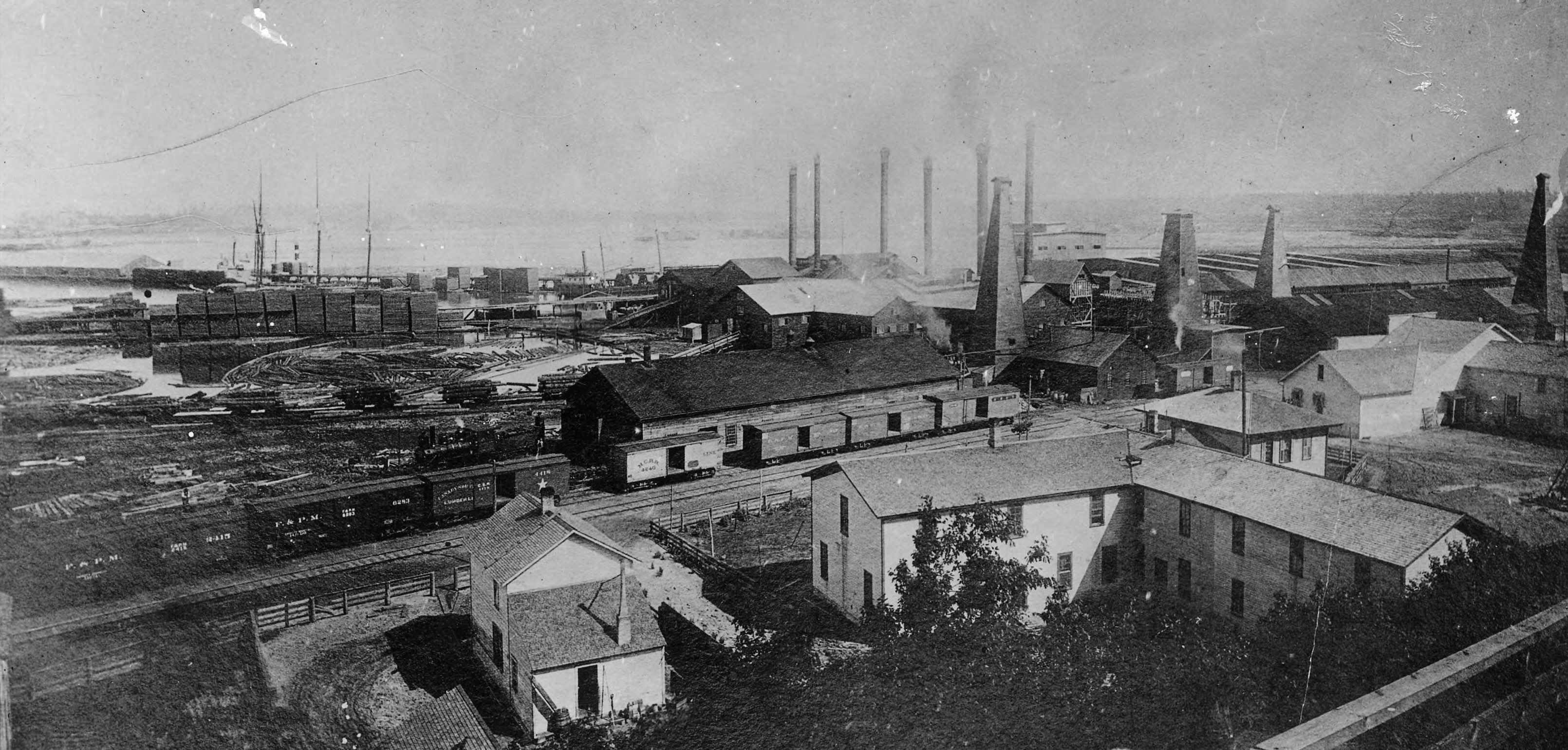 An aerial view of a sawmill with a railroad station next to it