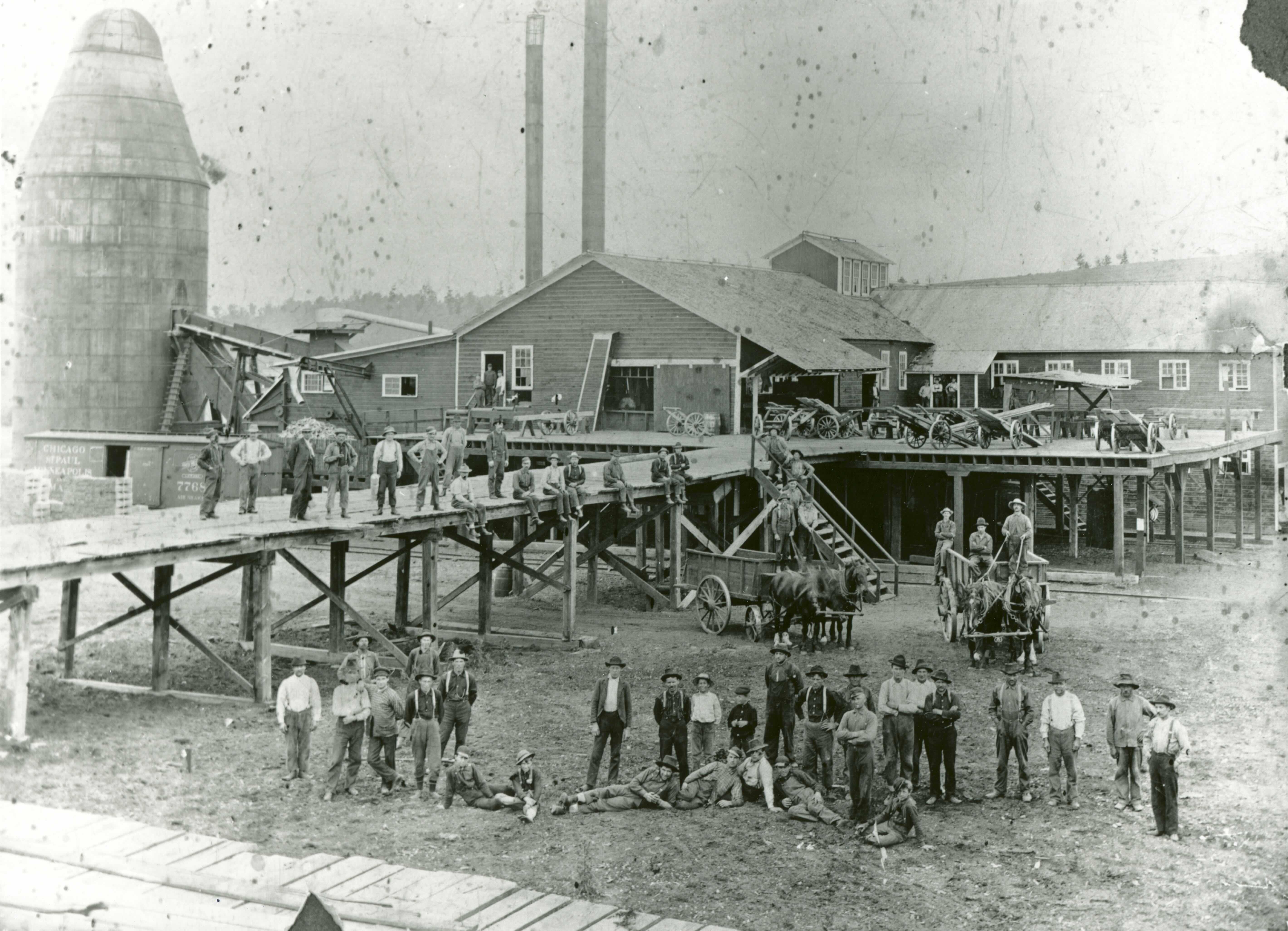 Men stand in front of a sawmill