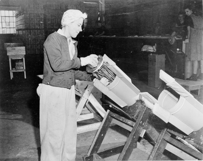 Worker packing parachute into cylinder